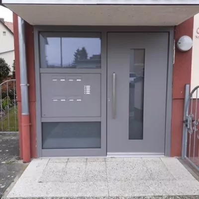 image001 graue-Haustuer-mit-Fensterelementen-fuer-Wohnungskomplex-mit-mehreren-Klingeln-und-Briefkaesten